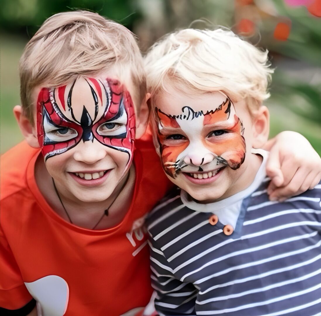 Two children with colorful face paint smiling.