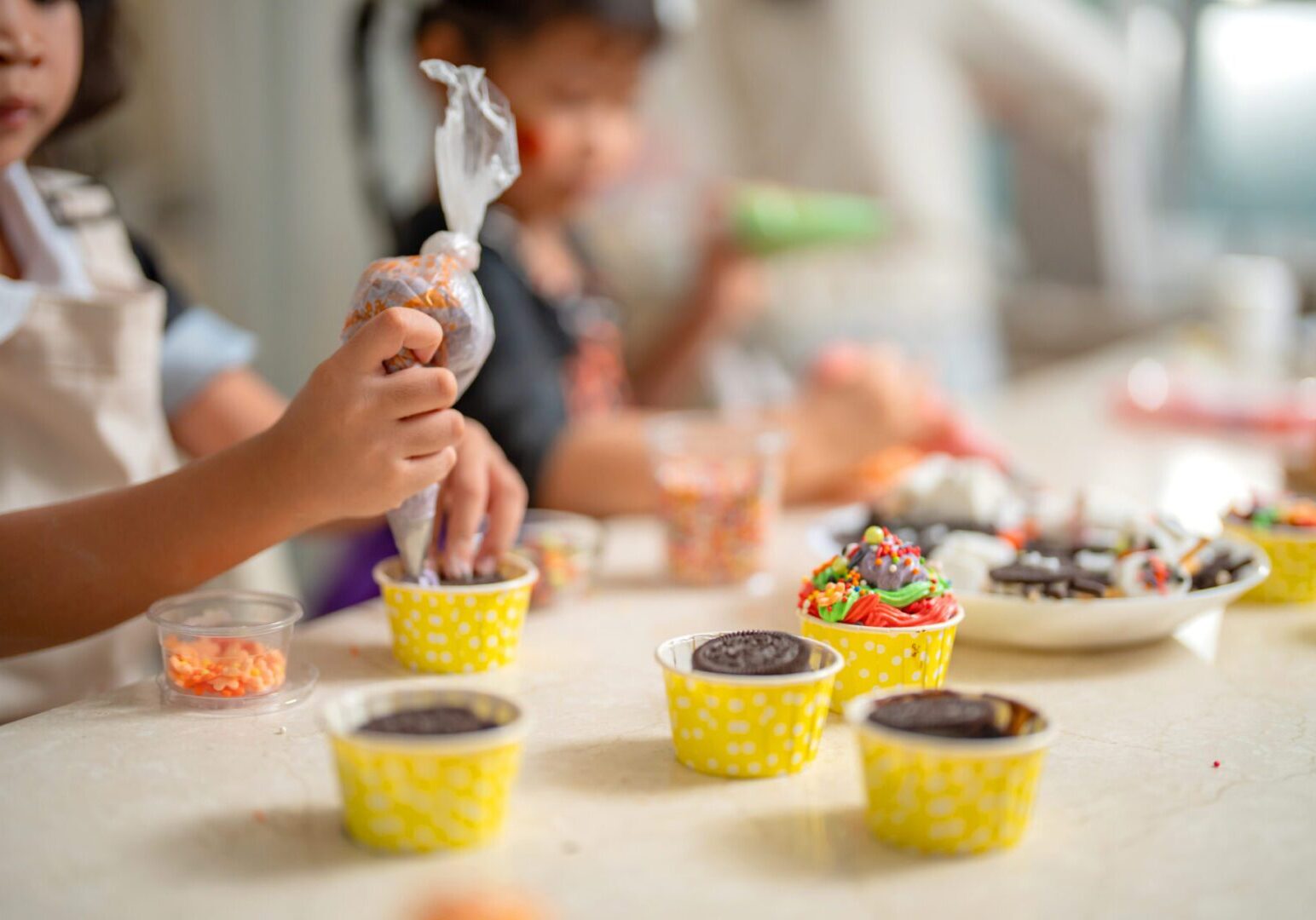 Asian family make cookies and cake for celebrating Halloween at home. Kid learning with Mom in cooking class.